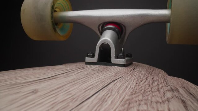 Camera moving alomg board of longboard. Dolly shot with laowa probe lens. Macro of skateboard. Close-up in 4K, UHD