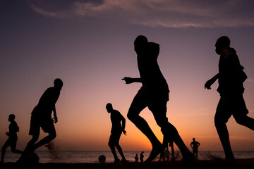 Silhouettes of football players at sunset on a beach in Senegal