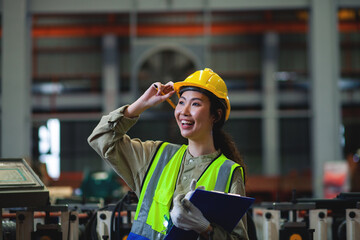A professional female worker of African descent works to inspect machinery in a manufacturing plant. Engineer uniform and safety helmet. copy space
