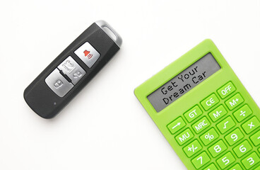 A flatlay picture of car key remote with calculator written get your dream car word. Auto loan concept.