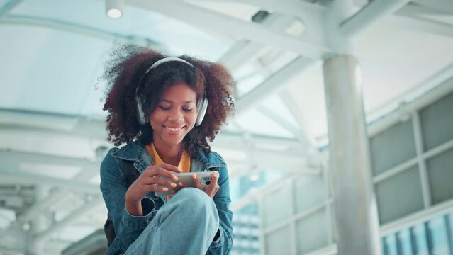 Young tourist African American woman wearing headphones and enjoying music on the urban city, Female listening to music on the town
