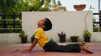 Little cute boy practicing yoga pose on a mat indoor. 