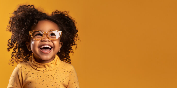 Happy little african american girl with big eyeglasses. Isolated on solid yellow background 