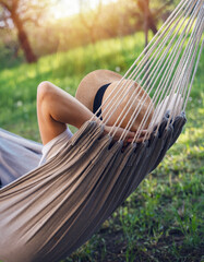 Woman in a hat lying on a hammock in a summer garden. Summer vacation vacation