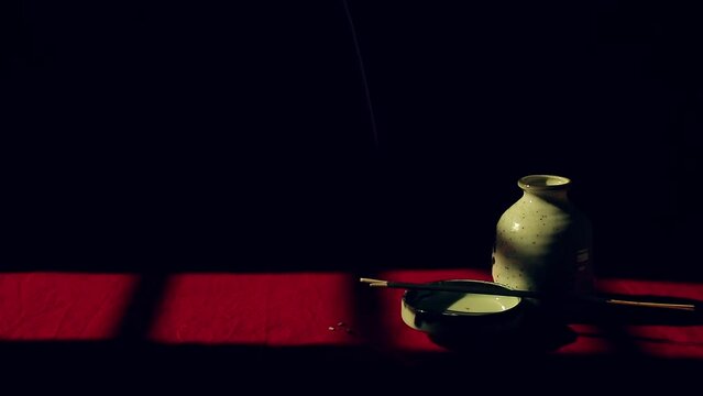 Incense sticks on a ceramic platter half hidden in the dark showing the concept of alternative holistic healing 