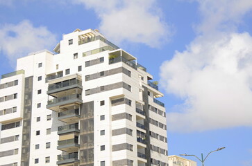 Fototapeta premium Modern residential area. Flowering trees near the new building. Luxury real estate. Investment in an apartment. Comfortable balconies and blooming Royal poinciana