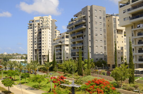 City for life. Beautiful modern urban area. Flowering trees, apartment buildings. Real estate in Israel. Scenic District