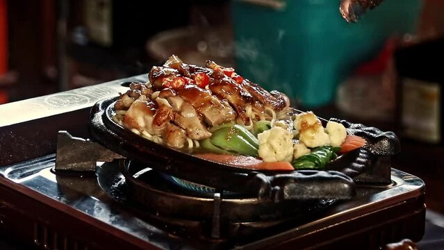 Mann oeng ktem sor marech or khmer roasted glazed chicken cooking in a hot plate, showing traditional authentic Cambodian cuisine and culture