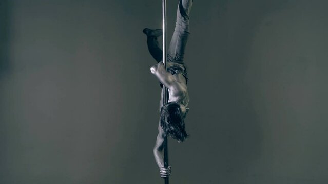 Pole dancer. Guy does gymnastic exercises on pole dance. Pole dancing for slim fitness body. Flexibility. Pole dance. Pylon dancing strength, flexibility, and grace. Strip muscular man dancer.