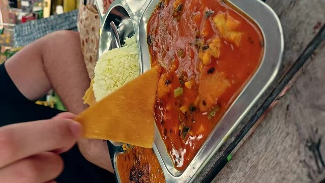 Tourist eating papadum as part of a chicken thali set, authentic traditional indian food