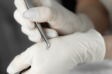 Photo of artificial eyelashes close-up. Beautician in white gloves holds his eyelash with tweezers and points to the camera. Preparation for eyelash extensions.