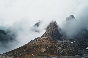 Mountain landscape with clouds and a person standing in front