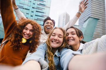 Teenager friends taking selfie portrait with cell phone outdoors in the modern city 