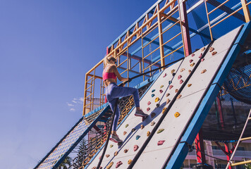 Athletic young woman working out and climbing a ropes at the rope training camp.