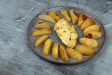 Fried Chicken breasts with potatoes on the plates above blue background