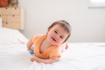 Obraz na płótnie Canvas lifestyle home portrait of happy and beautiful 8 months old baby girl mixed race Asian Caucasian playing cheerful on bed exploring the surroundings curious