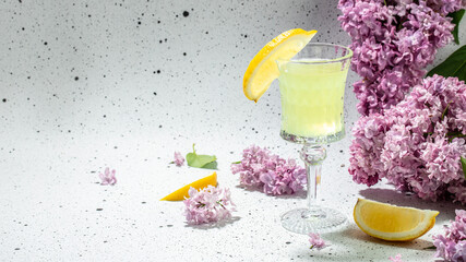 traditional liqueur limoncello with blooming lilac on a light background