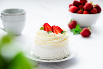 Pavlova meringue cake with fresh straberry and whipped cream mascarpone with mint leaf decoration. Recipe of traditional dessert Anna Pavlova. Homemade pastry.