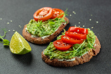 Avocado Toast and tomatoes on dark background. Vegetarian food. Vegan menu. place for text, top view