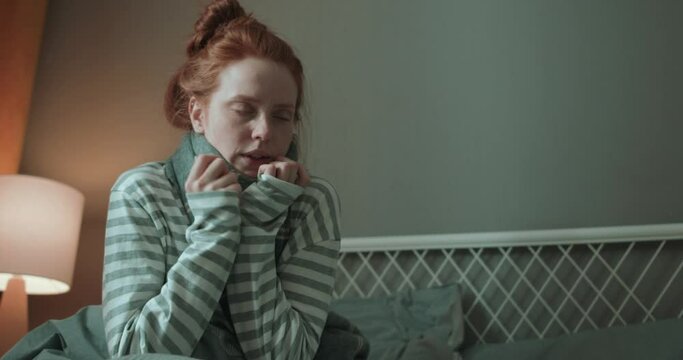 Young weak redhead ginger woman has no stength she poes to bed, coving with warm blue blanket, Slow motion