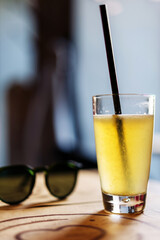 Drink glass with plastic drinking straw and healthy citrus on the table in cafe.