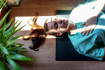 Yoga breathing exercise, serene woman lying down on exercise mat on back with closed eyes and meditating. - obrazy, fototapety, plakaty