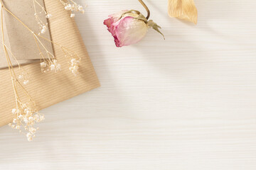 pretty Dried roses and hazel flowers on a book placed on a white wooden background	