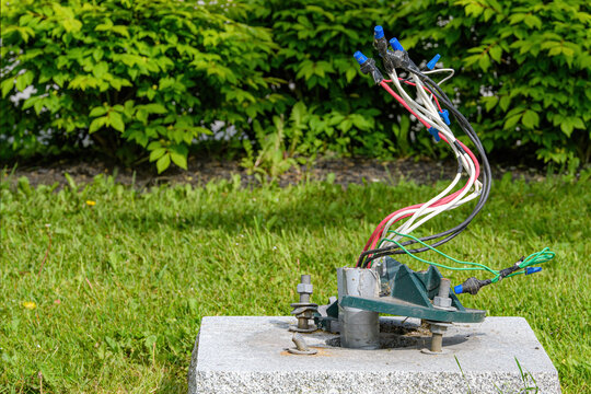 Wires for a street light. The street light pole is missing, a bit of it can be seen broken at the bottom. Wires are capped.