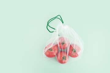 mesh fruit bag with tomatoes on natural green background