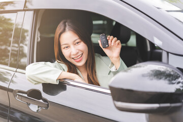 Dealership automobile, smile asian young woman, happy girl sitting in new car after purchase success, showing, holding auto remote key of vehicle, owner driver female buy gift for yourself at showroom