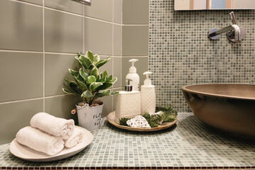 A fragment of the bathroom. Stylish accessories on the countertop decorated with mosaic tiles....