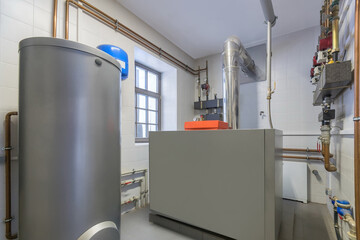 Autonomous boiler room in a private house. Large grey tanks and a pipe system with pressure gauges,...