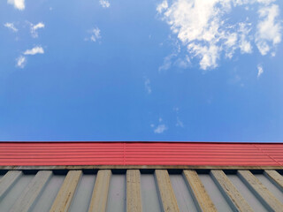 Naklejka na ściany i meble 少し雲がある青空と赤と灰色の金属の壁