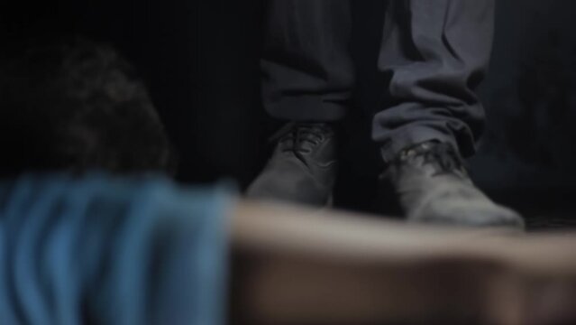 Shot of a man coming closer to a dead man on the floor in a dark room, Hd footage.