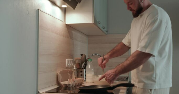 Portrait of happy bearded guy using whisk as microphone singing and dancing in kitchen while preparing dessert Cheerful man having fun cooking dinner happiness entertainment