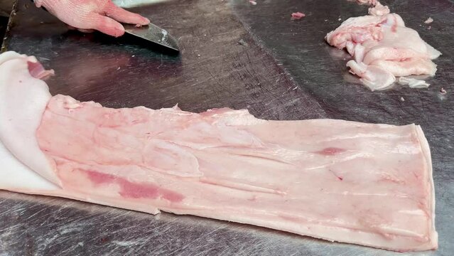 4K Cut the pork carcass with a knife. The butcher separates the fat from the carcass. Work in a meat shop on a maket