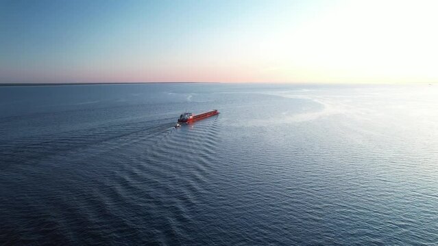 Aerial shot of a cargo ship in the open blue sea - top down view, the concept of export-import freight transport, a container ship transports goods by sea.