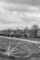 Obraz premium Run-down rusty radio satellite dishes lined up next a footpath, with a cloudy overcast sky