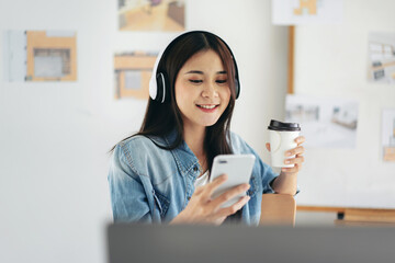 Woman architect drinking coffee and wearing headphone to listeni