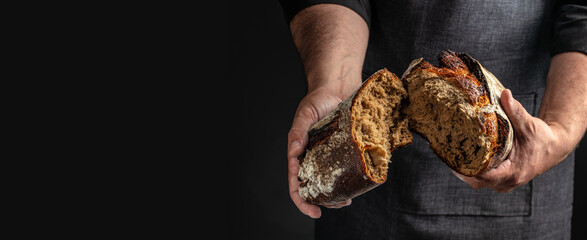 Male hands breaking freshly baked bread, Long banner format