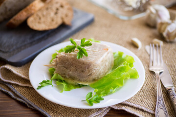 Boiled chicken meat aspic in meat gelatin broth in a plate