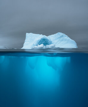 Split view of an iceberg showing above and below the water line. Underwater iceberg. Antarctica. Arctic Greenland. Climate change and global warming travel concept.
