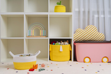 Children room with shelves and colorful storage baskets and boxes. Rainbow wooden toys. Space...