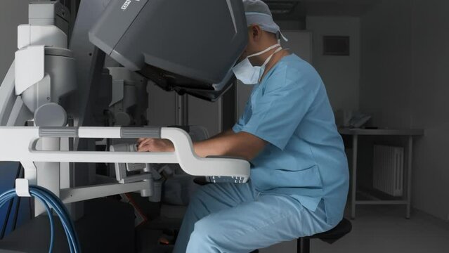 Workplace of surgeon using modern minimal invasive robotic medical system. Doctor watches operation through stereo vision headset and controls manipulators in 3D space with joysticks