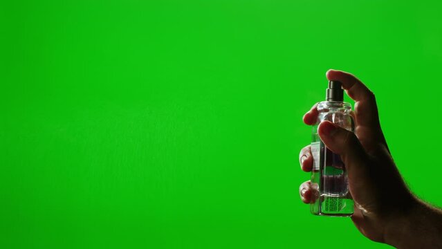 Young man applying perfume to skin on chroma key green screen, close up of spraying deodorant luxury perfume.