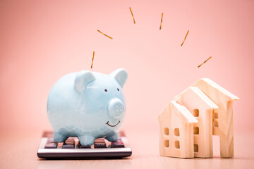 Piggy bank put on the calculator and home model and dropping gold coin with working capital...