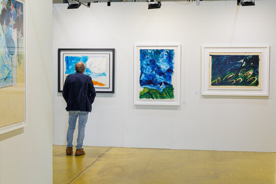 Parma, Italy - october 2022: Man Admiring Paintings in a Modern Art Gallery.