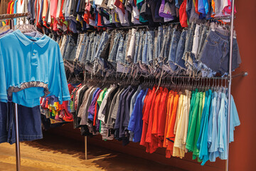 Colorful Polo, T-shirts and Summer Jeans Shorts Hanging in a Coat Rack inside a Store