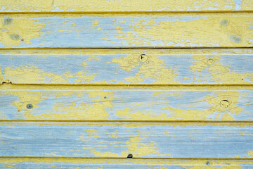 The texture of cracked yellow paint on a wooden wall
