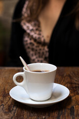 White cup with espresso coffee on a wooden table in a coffee shop.
